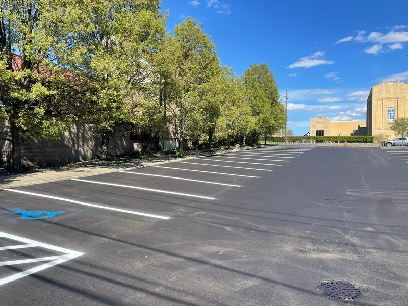 New white stall lines and a blue accessible-parking symbol on a freshly paved city lot