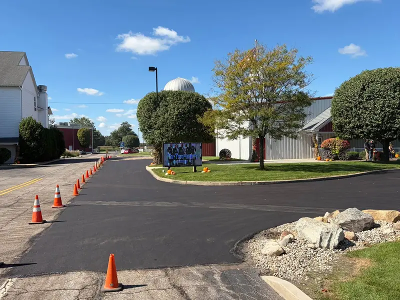 New asphalt at the entrance drive of the Blue Gate campus in Shipshewana, with the cones still out