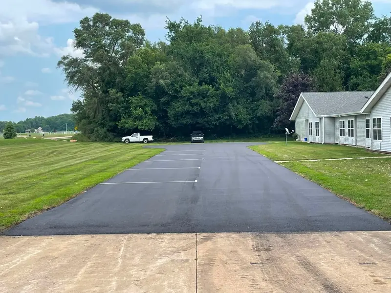 After: the same entrance drive repaved, with fresh white stall lines