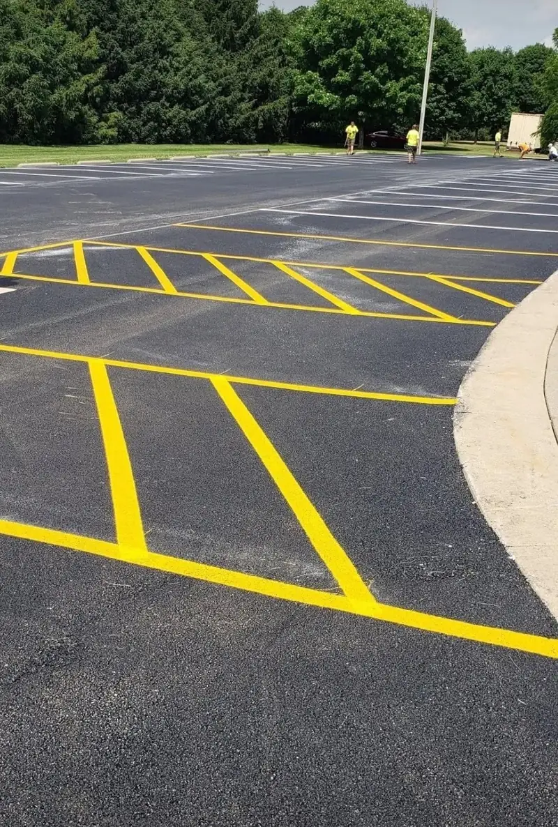 Freshly paved parking lot with new yellow striping and hatched no-parking zones