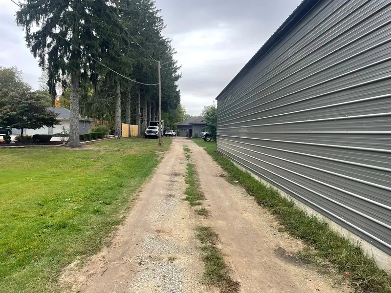 Before: a rutted dirt and gravel two-track running alongside a gray steel building